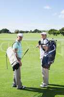 Golfer friends smiling at camera holding their golf bags