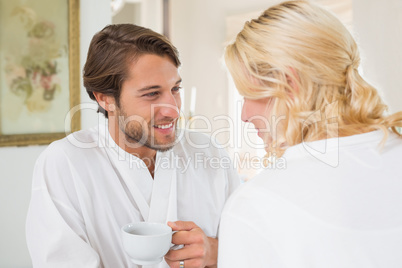 Cute couple in bathrobes having coffee together