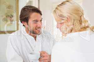 Cute couple in bathrobes having coffee together