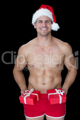 Smiling muscular man posing in sexy santa outfit offering gifts