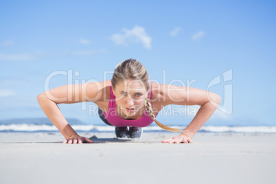 Fit blonde in plank position on the beach