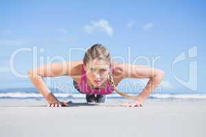 Fit blonde in plank position on the beach