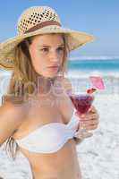 Pretty blonde holding cocktail on the beach