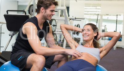 Trainer watching client do sit ups on exercise ball