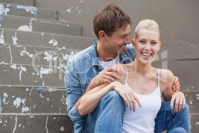 Hip young couple in denim sitting on steps