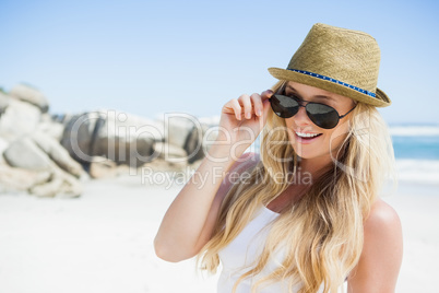 Stylish blonde smiling at camera on the beach