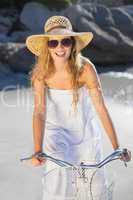 Beautiful smiling blonde in sundress on bike at the beach