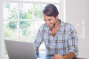 Smiling casual man using laptop to shop online