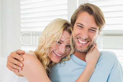 Cute casual couple sitting on couch laughing at camera