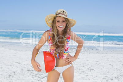 Fit blonde in white bikini and straw hat holding beach ball