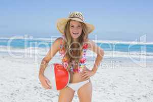 Fit blonde in white bikini and straw hat holding beach ball