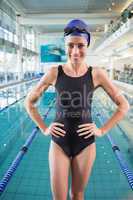 Fit swimmer standing by the pool smiling at camera