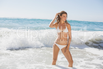 Beautiful smiling woman in white bikini standing in the sea