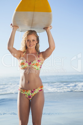 Gorgeous blonde surfer in bikini holding her board