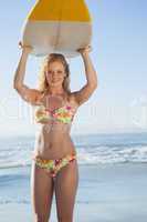 Gorgeous blonde surfer in bikini holding her board