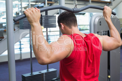 Strong bodybuilder using weight machine for arms