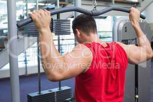 Strong bodybuilder using weight machine for arms