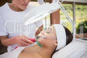 Peaceful brunette getting micro dermabrasion from beauty therapi