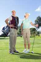 Golfing couple standing and looking around