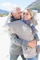 Carefree couple hugging on the beach in warm clothing