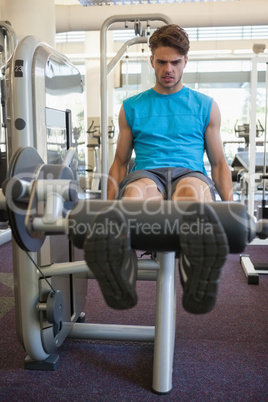 Focused man using weights machine for legs