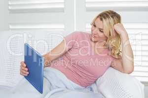 Happy blonde relaxing on the couch with her tablet pc