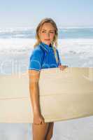 Blonde smiling surfer holding her board on the beach