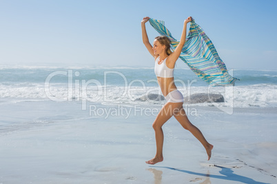 Gorgeous fit blonde running by the sea with scarf