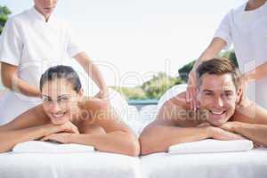 Smiling couple enjoying couples massage poolside