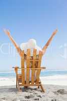 Woman sitting in deck chair at the beach with arms up