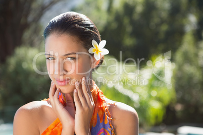 Brunette in sarong smiling at camera by the pool
