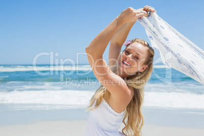 Pretty carefree blonde posing on the beach with scarf