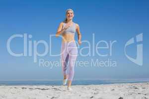 Sporty blonde on the beach jogging towards camera