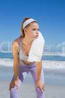 Sporty blonde standing on the beach with towel