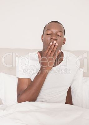 Tired man yawning in his bed