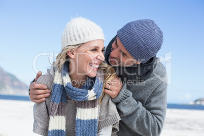 Attractive couple embracing on the beach in warm clothing
