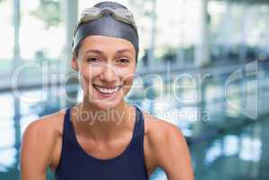 Pretty swimmer smiling at camera by the pool