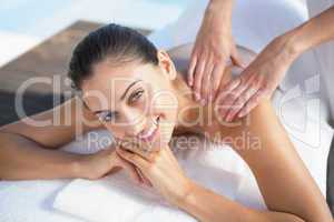 Happy brunette enjoying a massage poolside