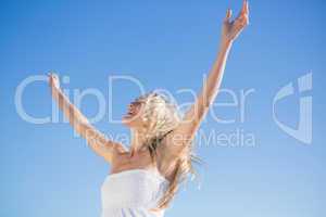 Woman in white dress standing with arms outstretched
