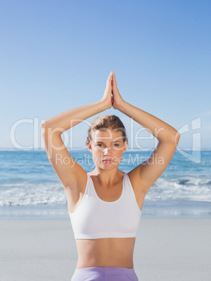 Sporty blonde sitting in lotus pose on the beach