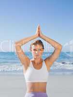 Sporty blonde sitting in lotus pose on the beach