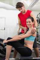 Trainer helping his smiling client on the rowing machine