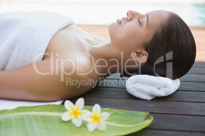 Peaceful brunette lying with eyes closed on a towel