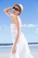 Pretty blonde in white dress and sunhat on the beach