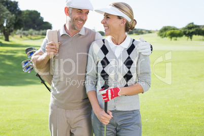 Golfing couple smiling at each other on the putting green