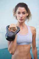 Fit woman looking at camera holding kettlebell