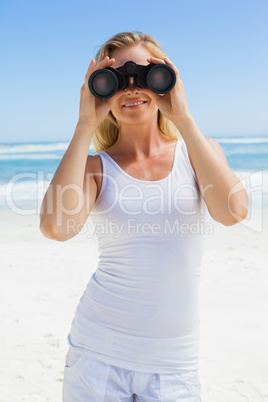 Blonde looking through binoculars on the beach