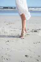 Woman in white dress stepping on the beach