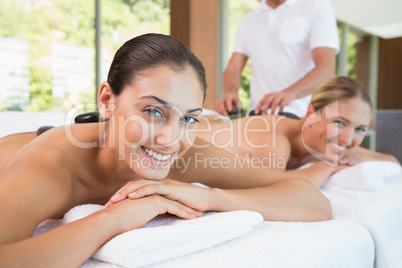 Pretty friends lying on massage tables with hot stones on their