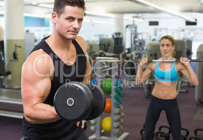 Muscular man and woman lifting weights